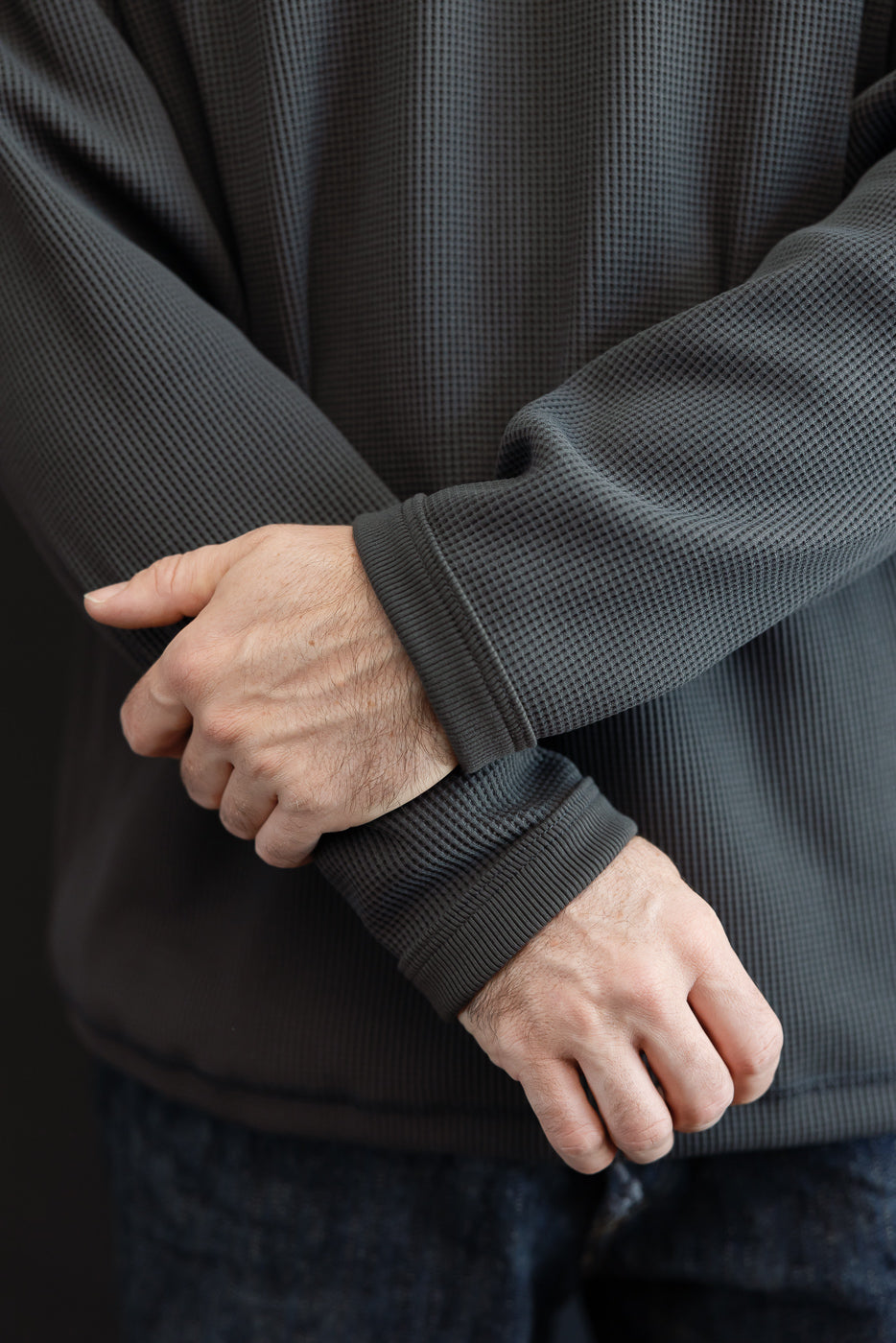 Close-up of male model’s arms in dark gray waffle knit long sleeve, showing ribbed cuffs and textured fabric
