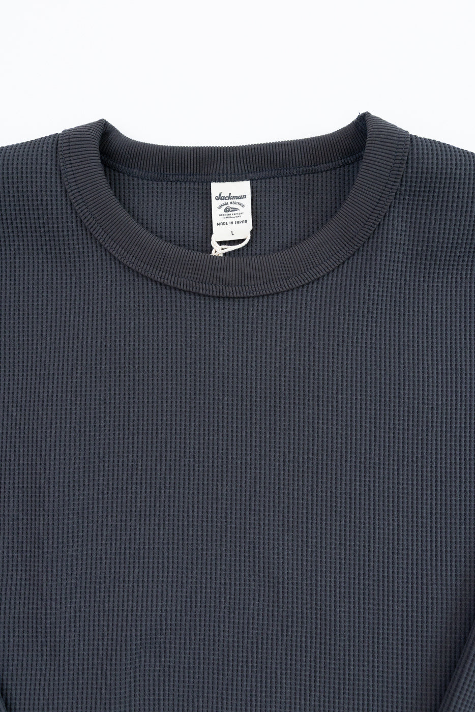 Close-up front view of dark gray waffle knit thermal shirt, showing ribbed crew neck and Jackman brand tag.