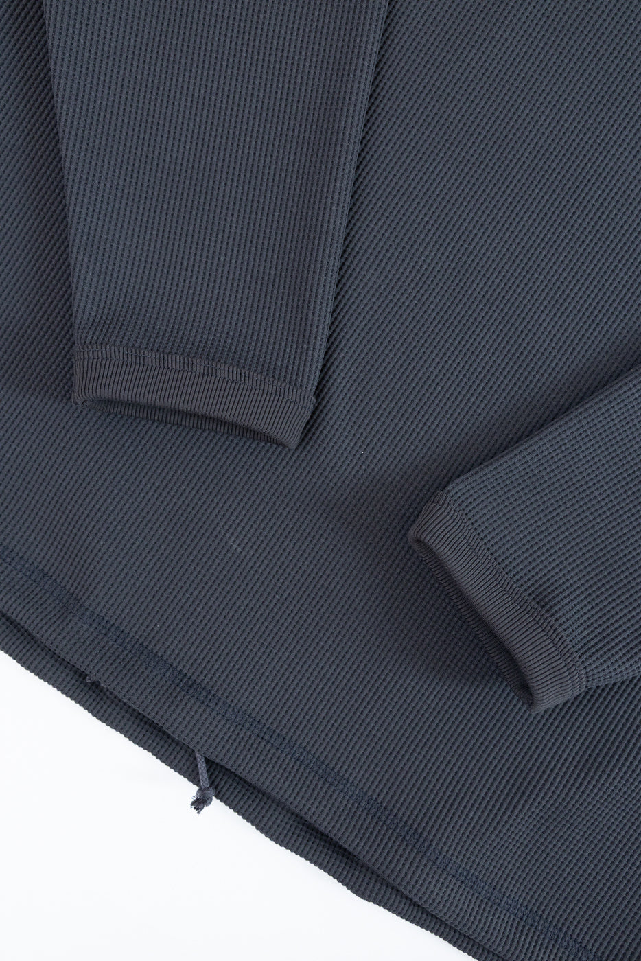 Close-up front view of dark gray waffle knit long sleeve shirt, showing ribbed cuffs and hem detail