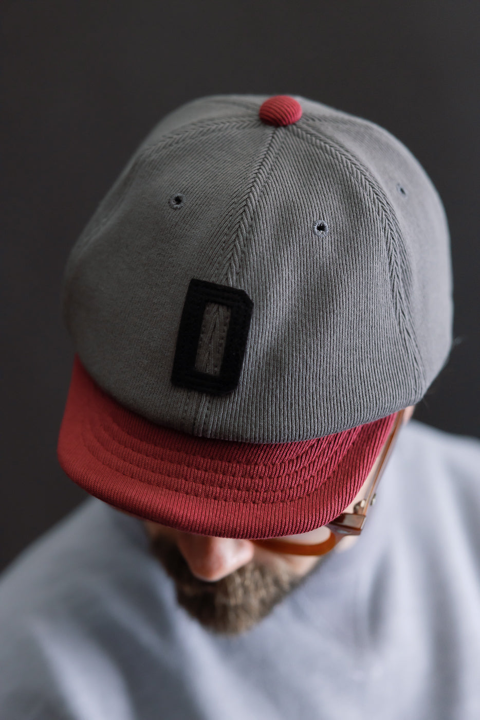 JM6310 - GG Rib BB Cap D - 318 Gray x Oxblood features a gray corduroy crown with black patch and brick-red visor, highlighting Jackman's sustainable, repurposed ribbed fabrics.