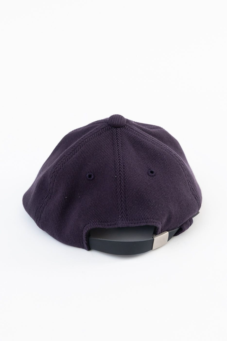 Back view flat lay of a dark purple corduroy baseball cap showing the adjustable strap.