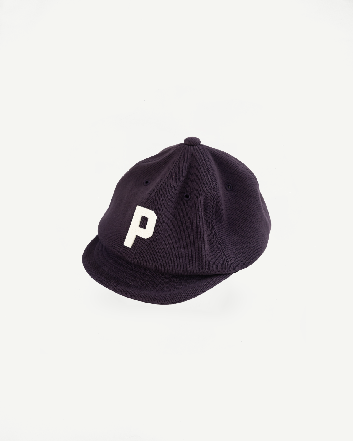 Close-up, front view of a navy corduroy cap featuring a white letter P embroidery.