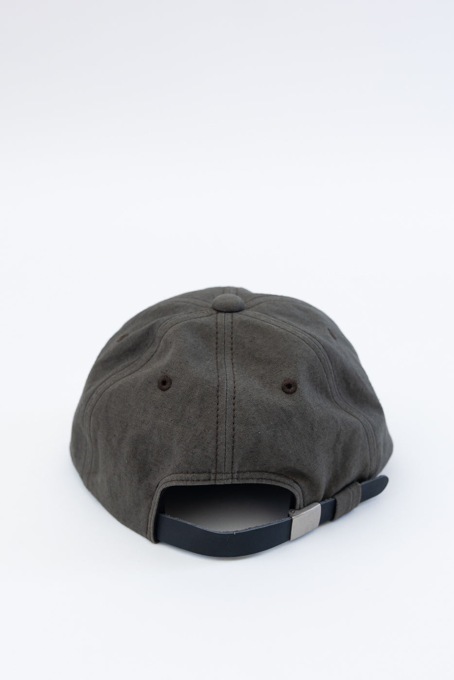 Close-up of the back of a dark moss gray canvas baseball cap showing adjustable strap and stitched eyelets.