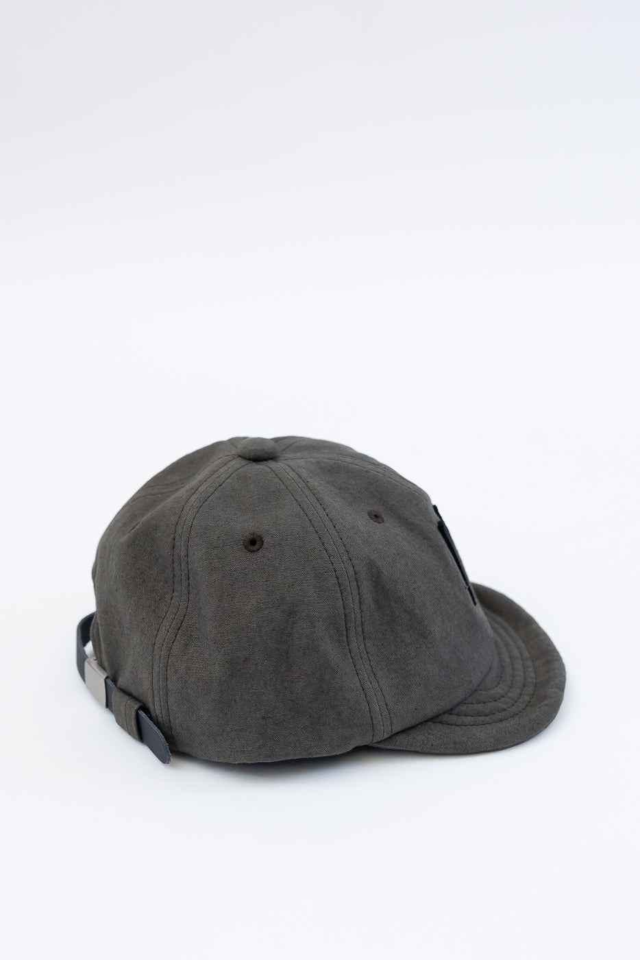 Close-up of back and side of dark moss gray canvas cap with adjustable strap and eyelets