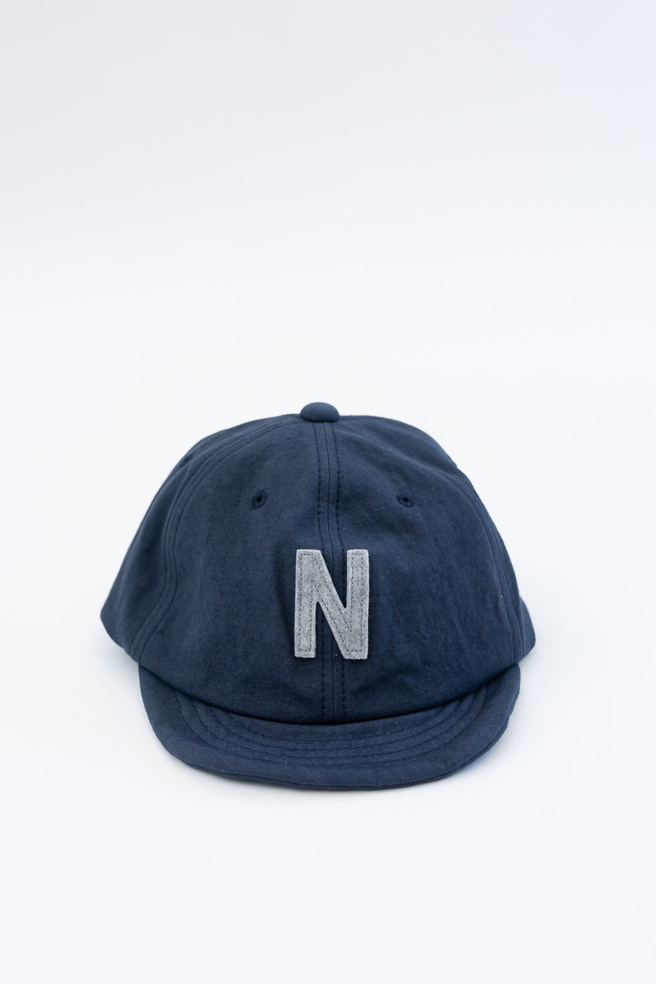 Front view close-up of navy canvas ball cap featuring a gray letter N applique detail.