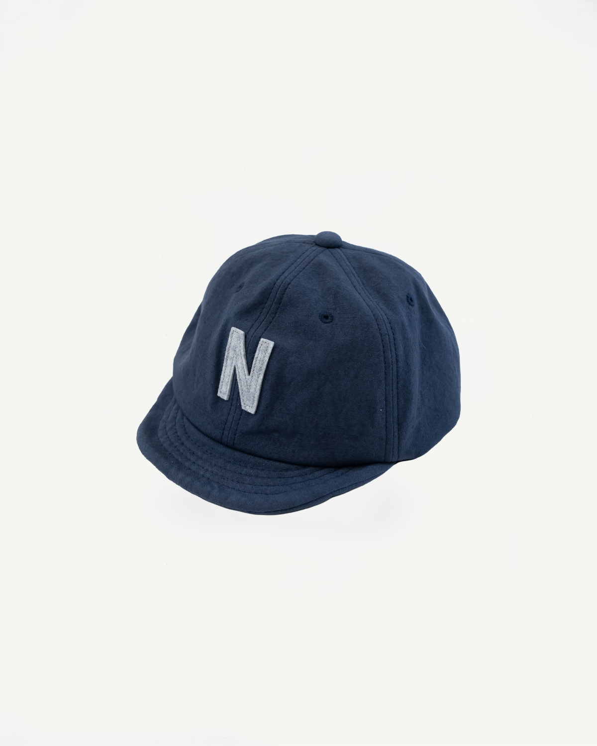 Front angled close-up of navy canvas baseball cap with raised embroidered N detail.