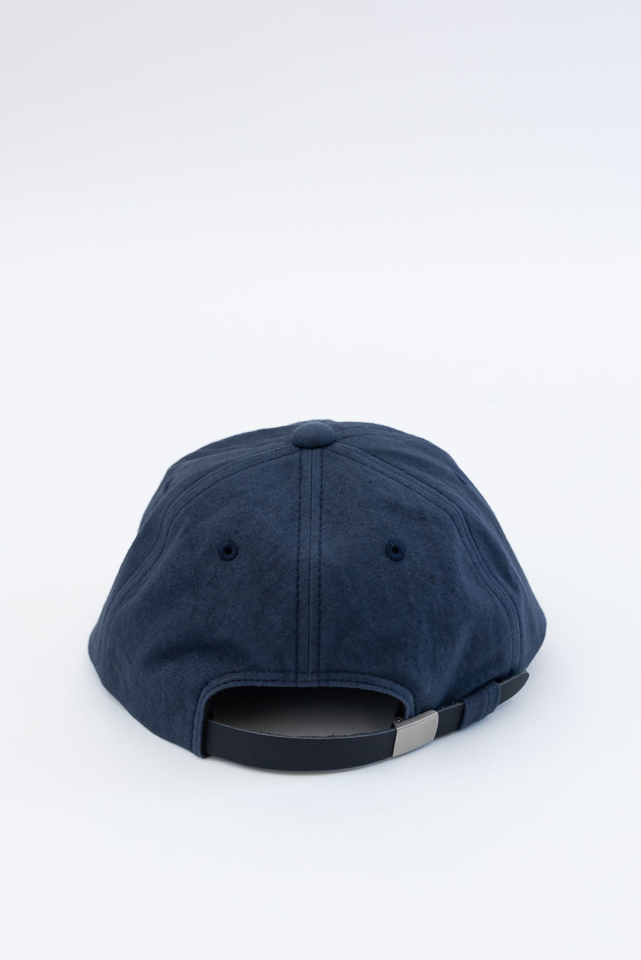 Close-up of navy canvas baseball cap, rear view showing adjustable strap and fabric texture.