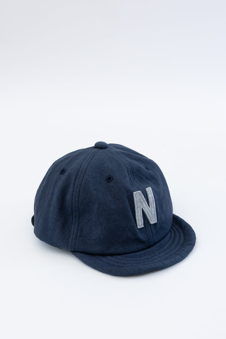 Front angled close-up of navy canvas baseball cap with raised embroidered N patch