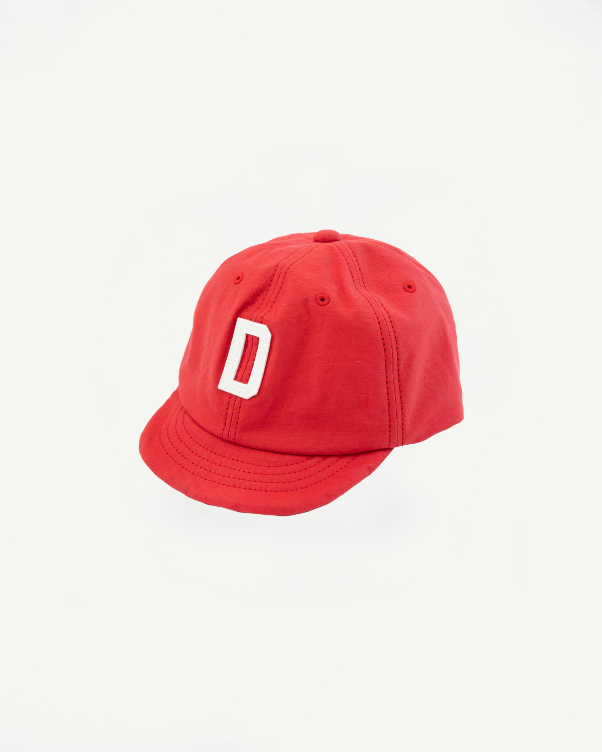 Red baseball cap with white 'D' logo, front view, showing curved brim and panel stitching
