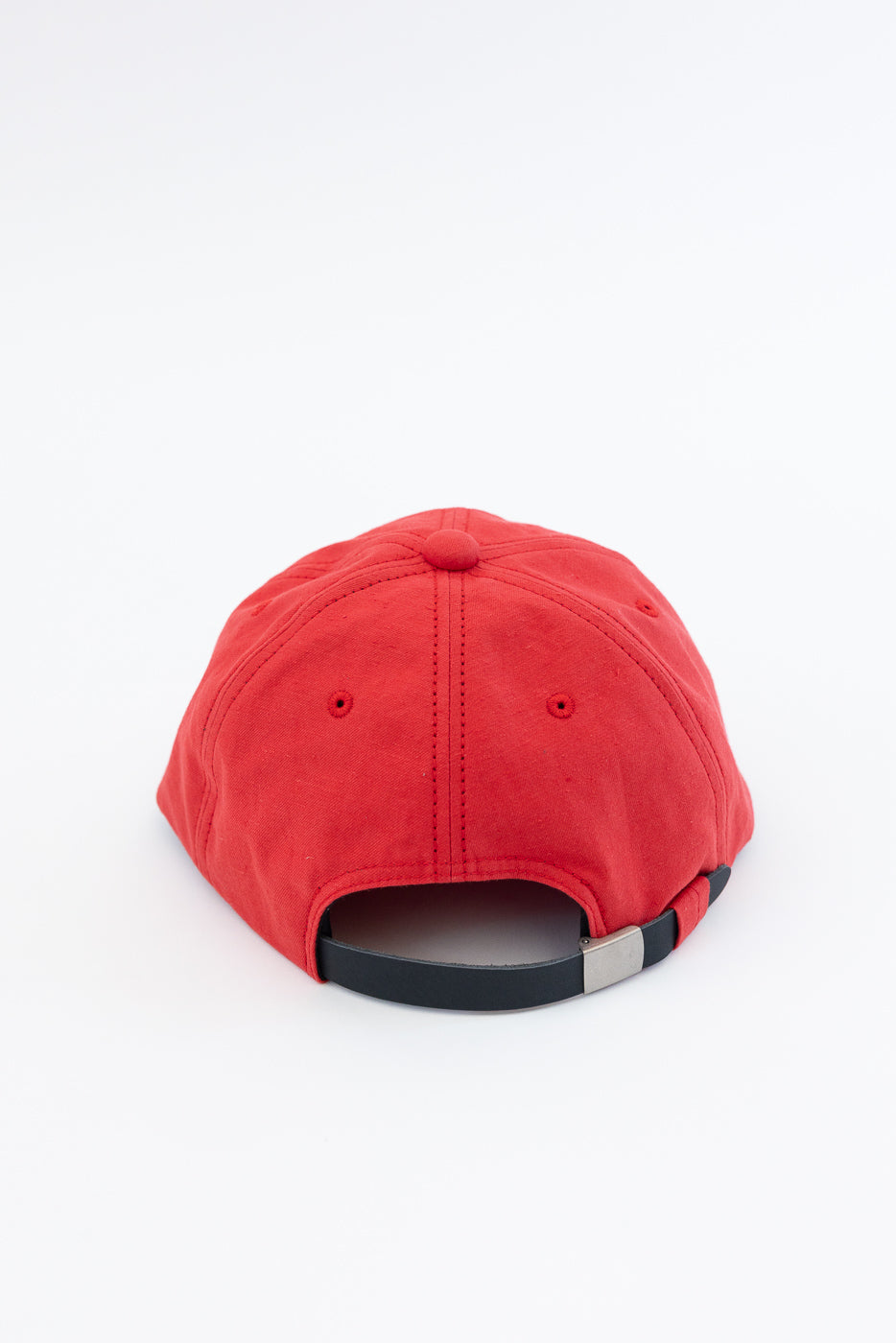 Back view of red baseball cap with black adjustable strap and silver buckle, showing fabric texture and stitching details