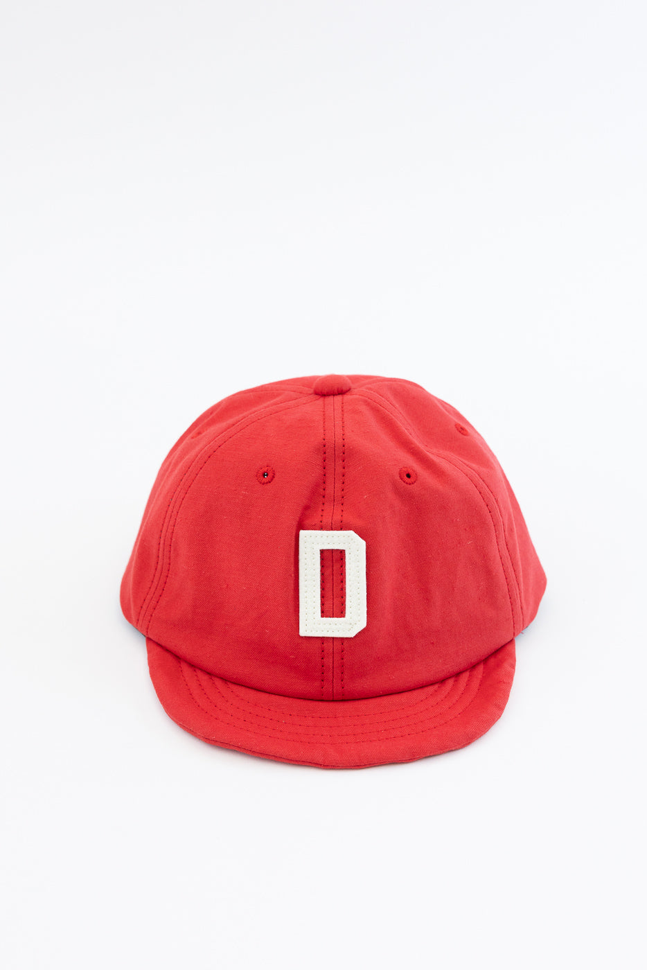 Red baseball cap front view, white 'D' patch, structured crown, curved brim, casual apparel accessory
