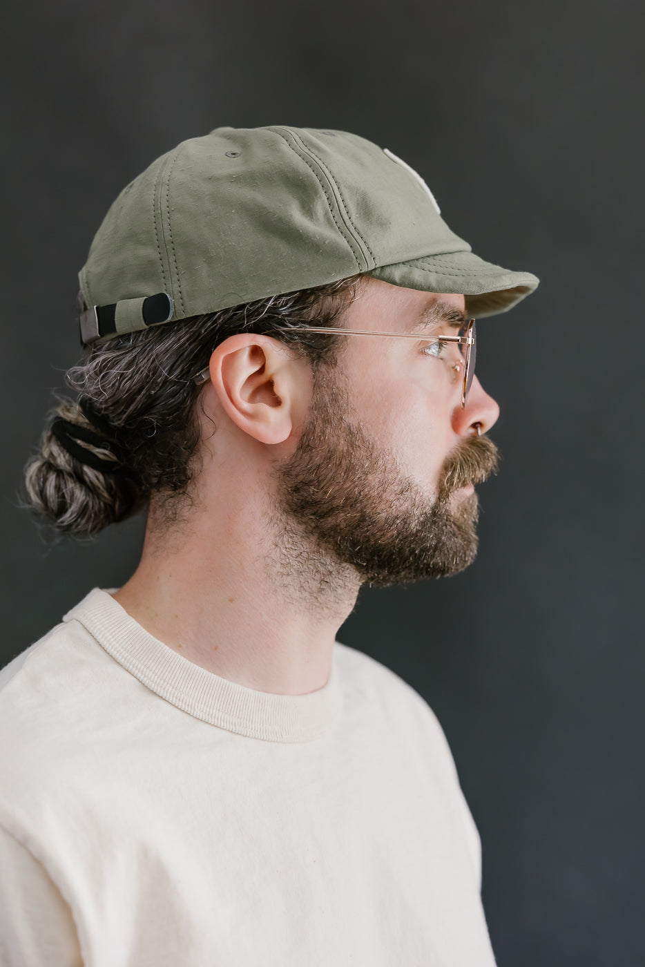 Man wearing a green cap and glasses against a dark background