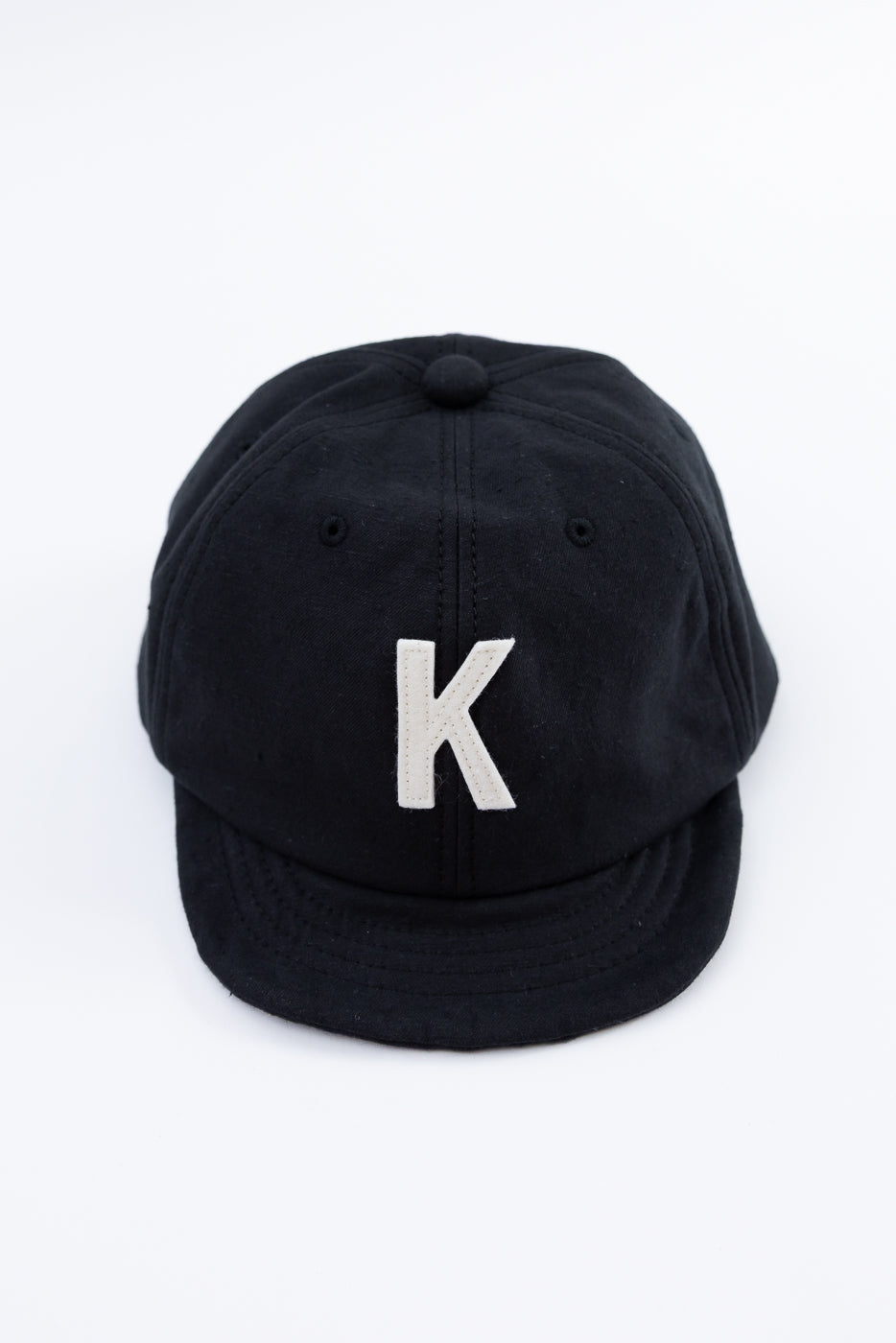 Black cap with a white 'K' on a white background