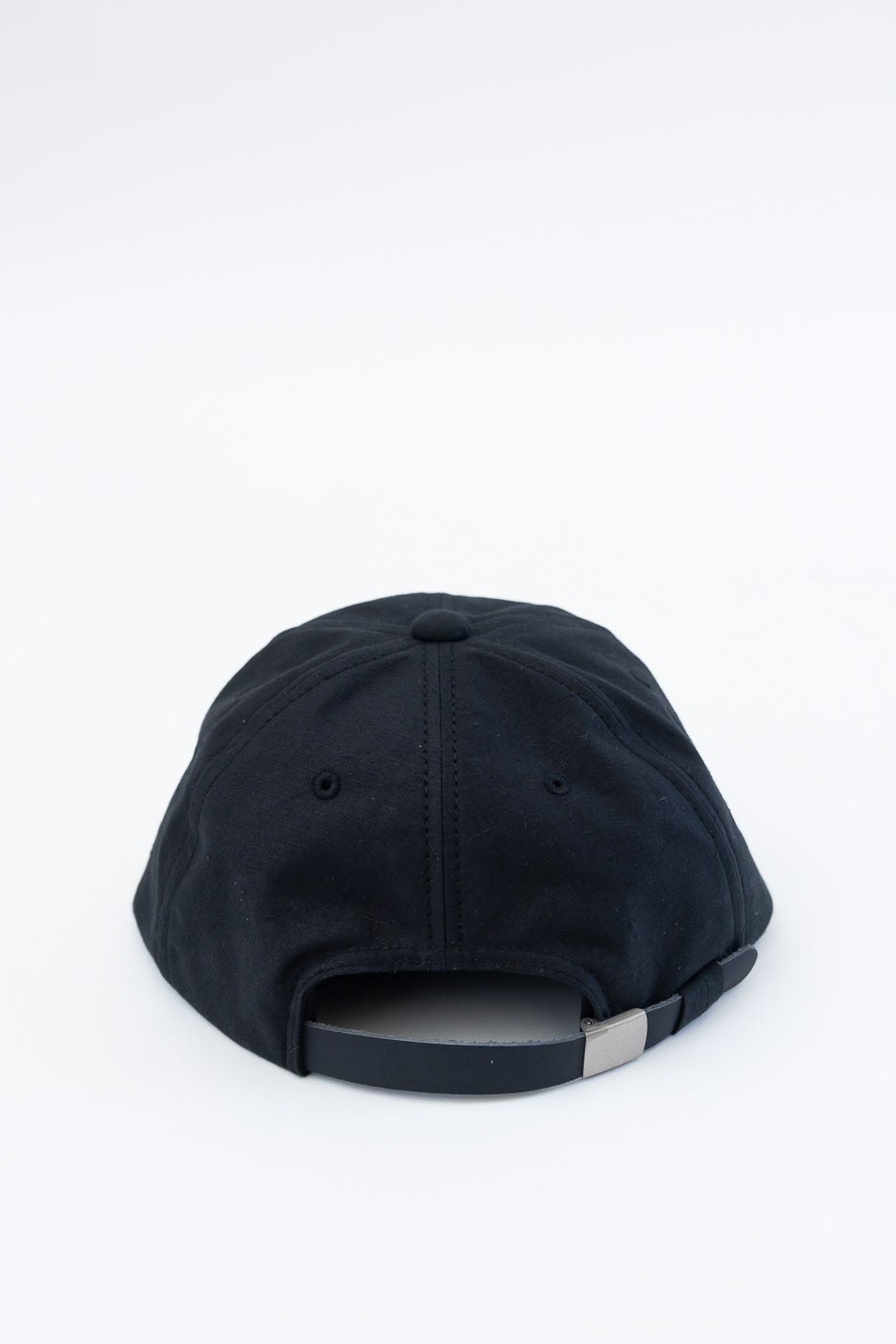 Back view close-up of black ball cap, showing adjustable strap and back panel stitching detail.