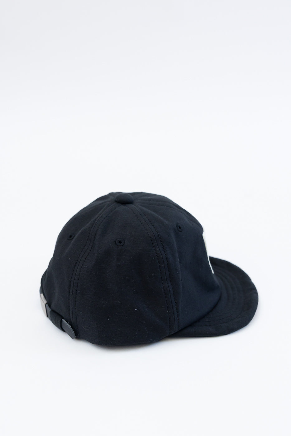 Close-up of black cap, back side view showing dome panels and adjustable strap detail.