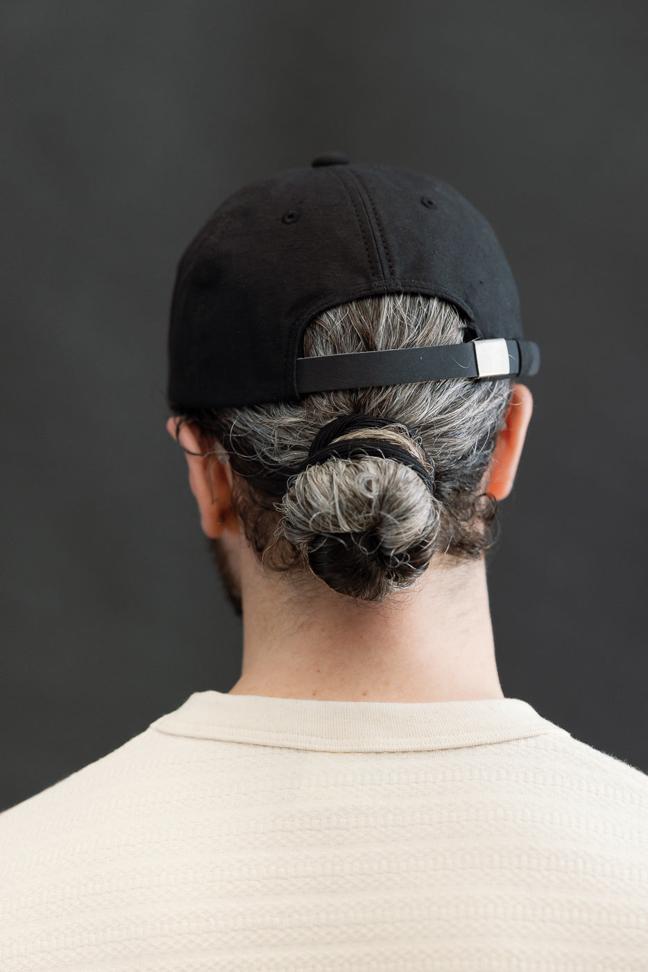 Close-up of the back of a black baseball cap on a male model, 5'9