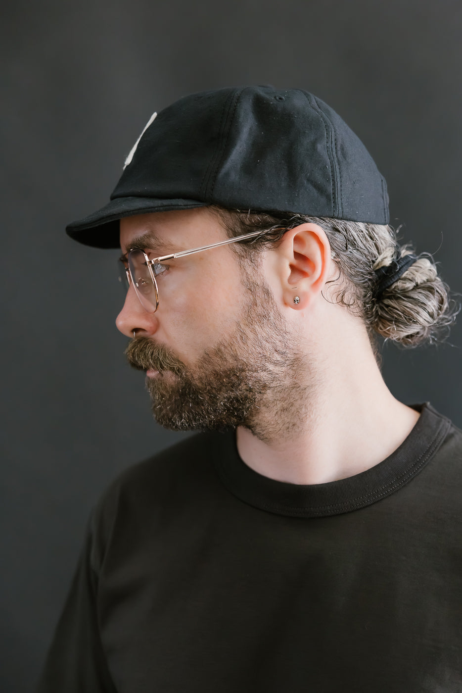 Man wearing a black cap and glasses against a dark background