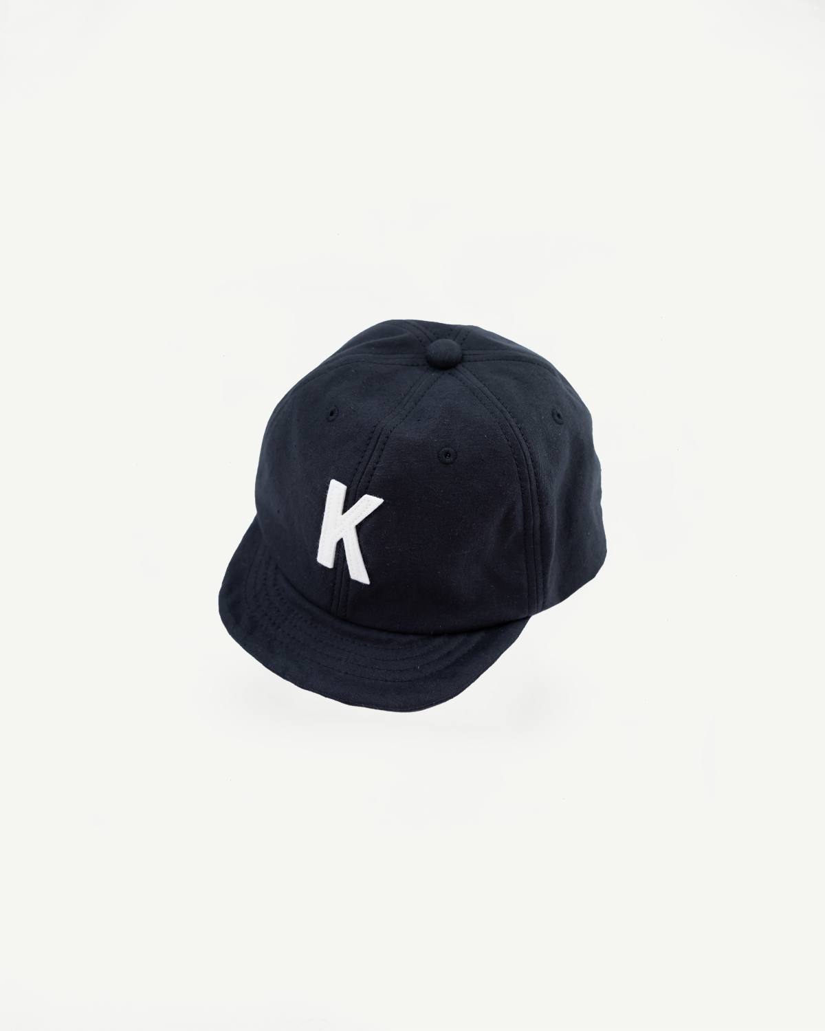 Black cap with a white 'K' logo on a light gray background