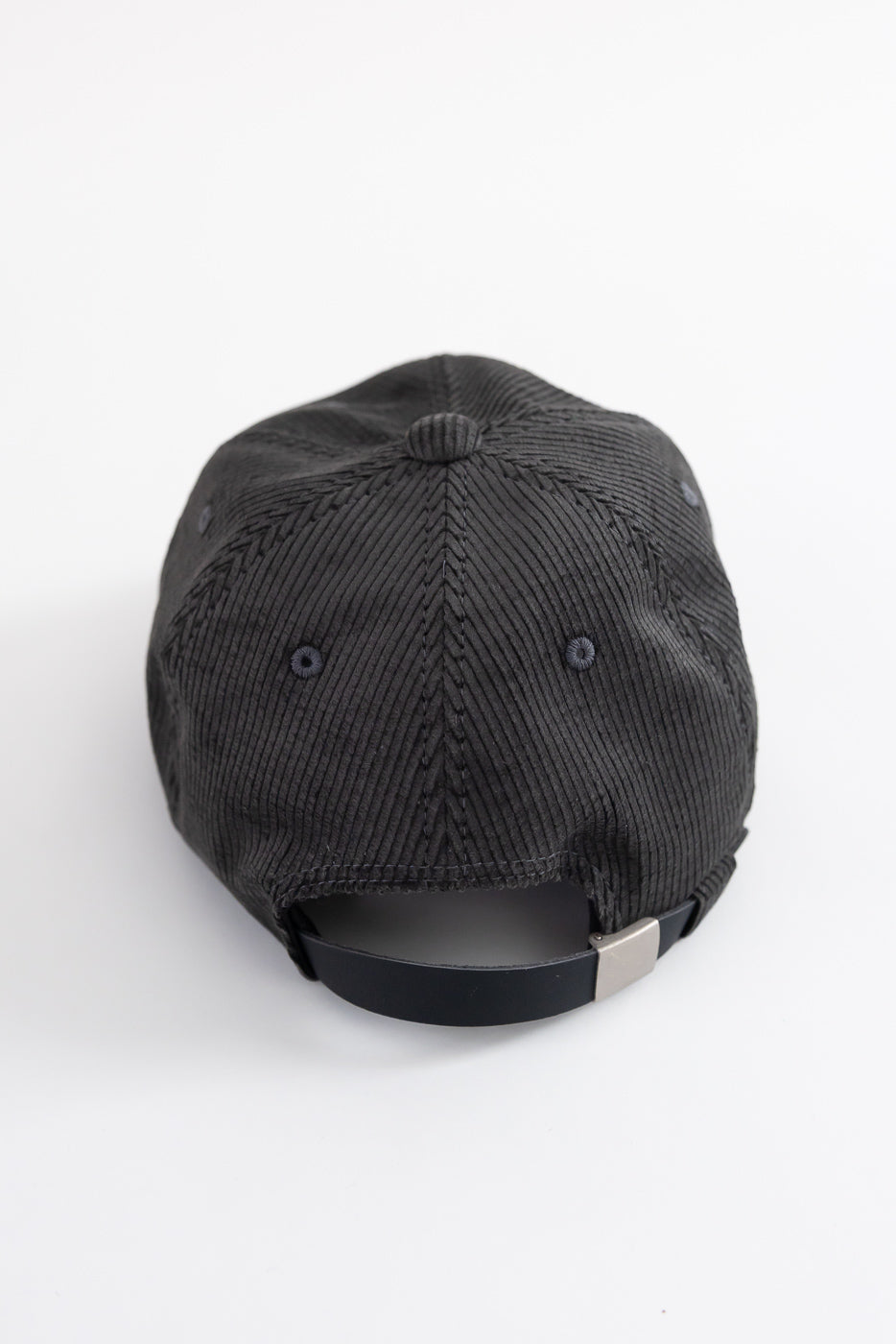 Close-up back view of fade black corduroy baseball cap, adjustable strap and textured fabric.