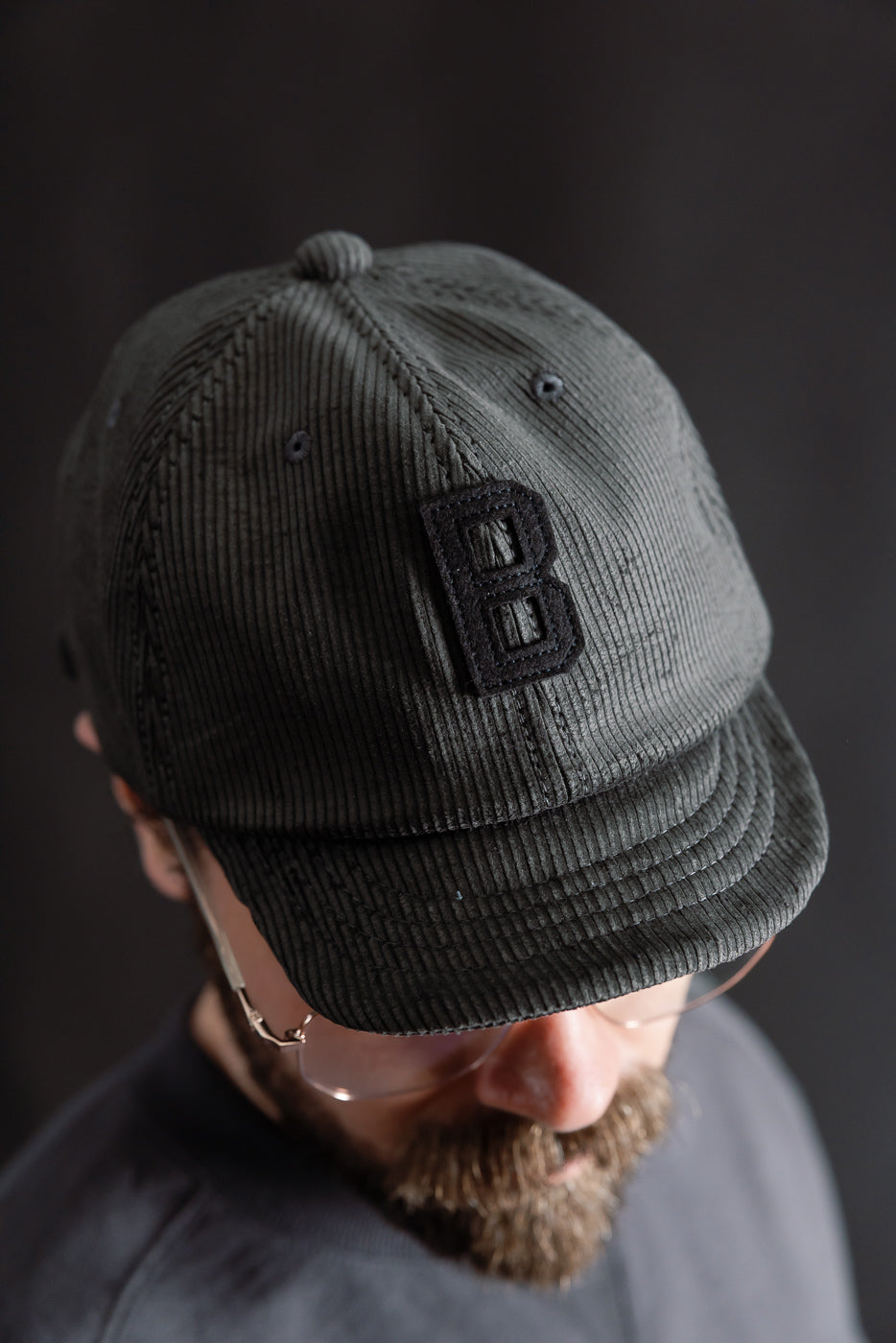 Close-up of black corduroy cap with embroidered B, front top view on male model, Dant apparel