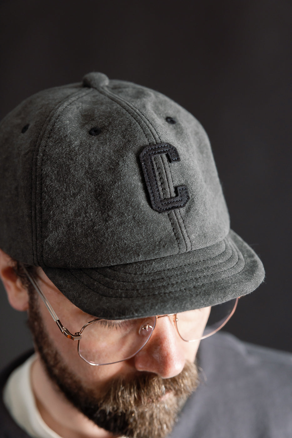 Close-up front view of black Jackman JM6575 cap with textured fabric, C patch, male model 5'9