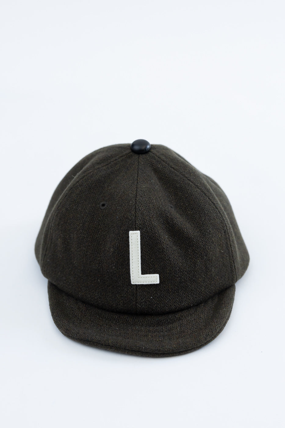 Front view close-up of olive melton wool baseball cap with white L patch and black top button