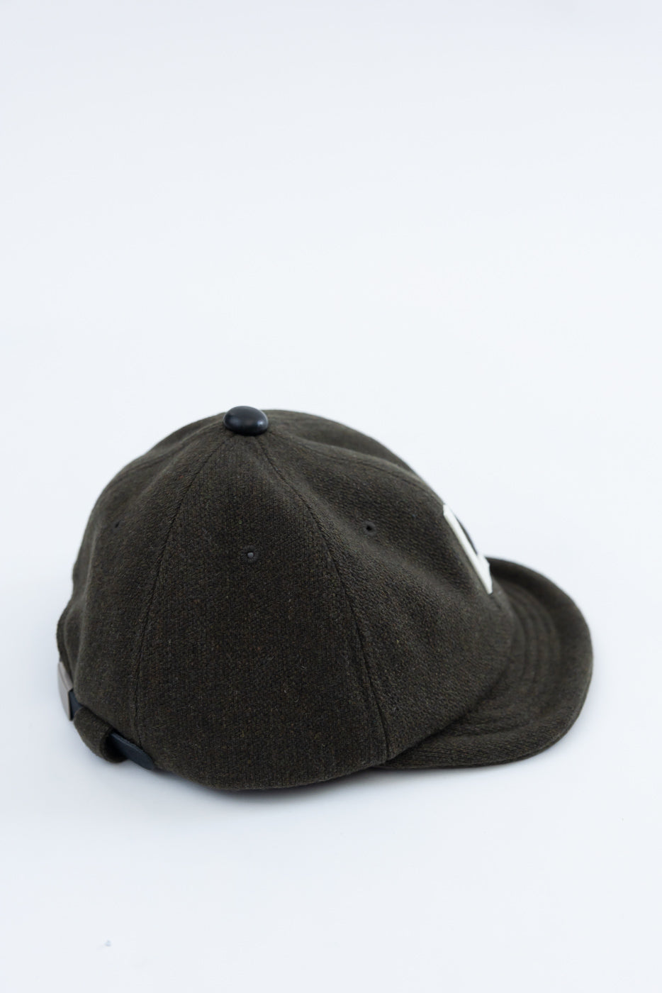 Close-up of olive green wool baseball cap, back and side view, showing fabric texture and adjustable strap.