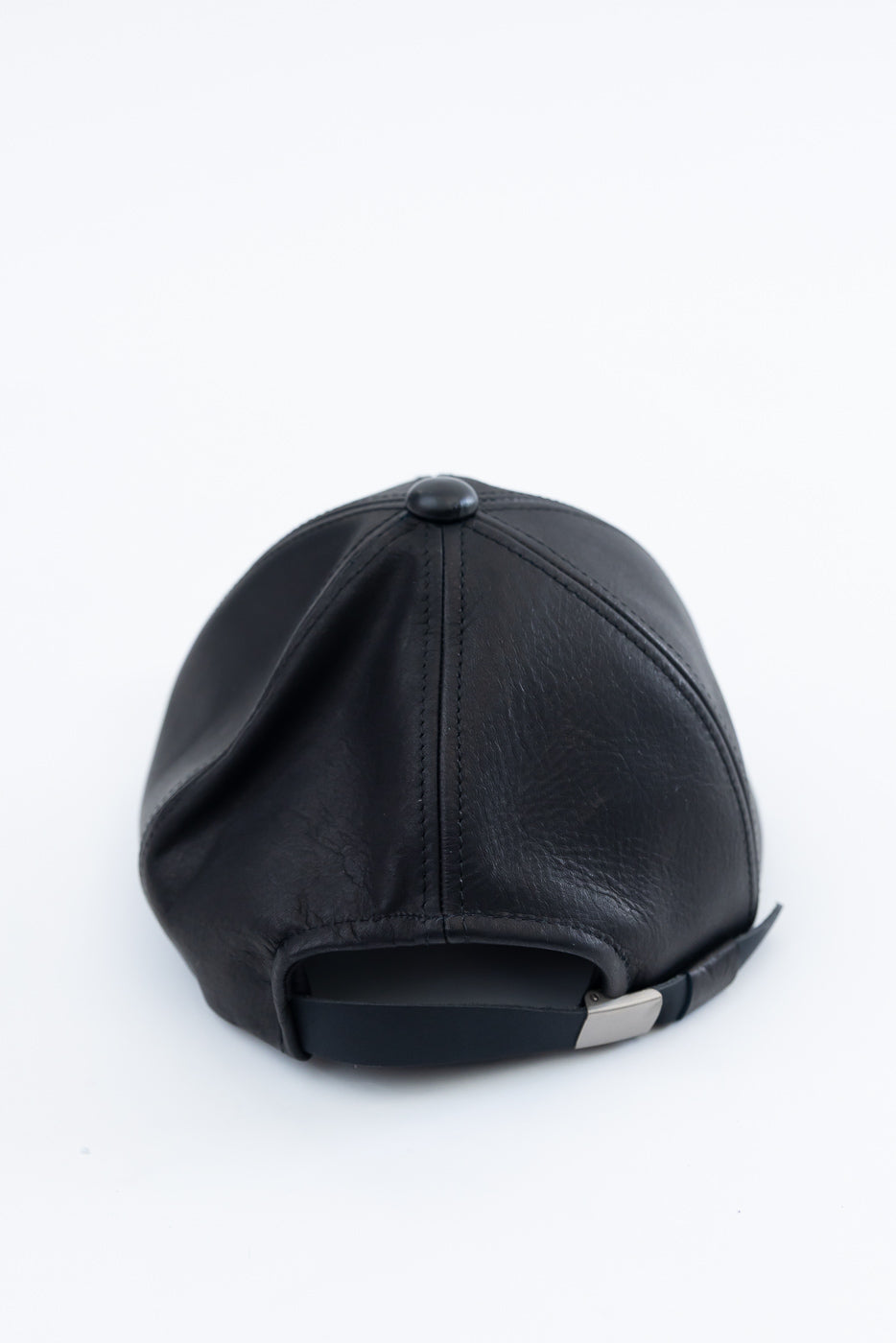 Close-up of the back of a black leather baseball cap showing adjustable strap and stitching detail.