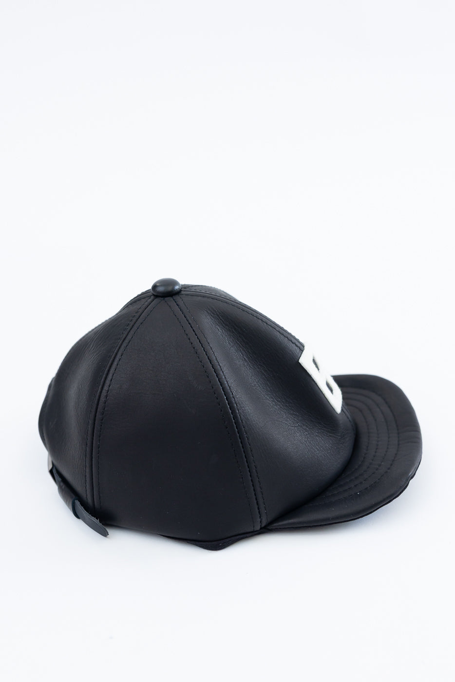 Close-up angled side view of black leather baseball cap showing back panels and stitched detailing
