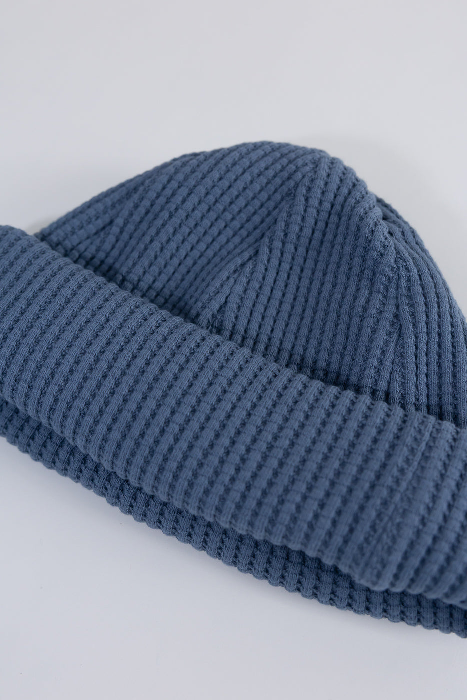 Close-up front view of retro saxe blue waffle knit cap, showing textured ribbed fabric.