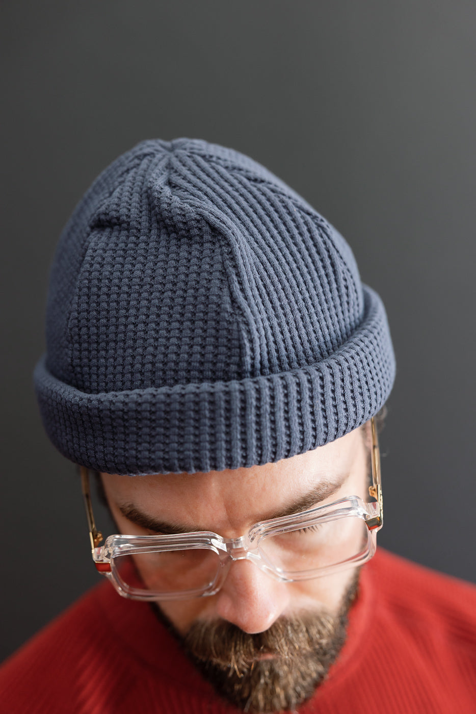Close-up front view of a blue waffle-knit beanie on a male model, 5'9