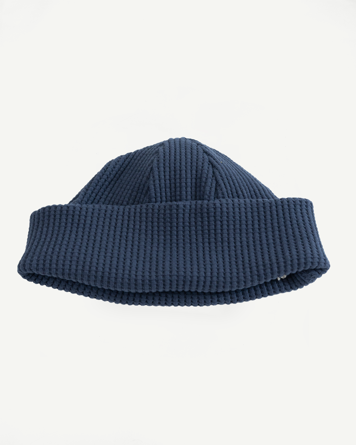 Front view flat lay of a navy blue ribbed knit beanie with a folded cuff.