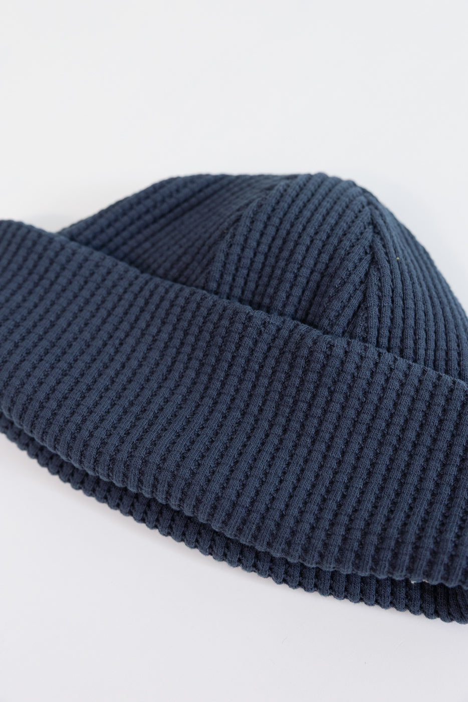 Close-up of the front side showing the waffle knit texture of a navy blue beanie.