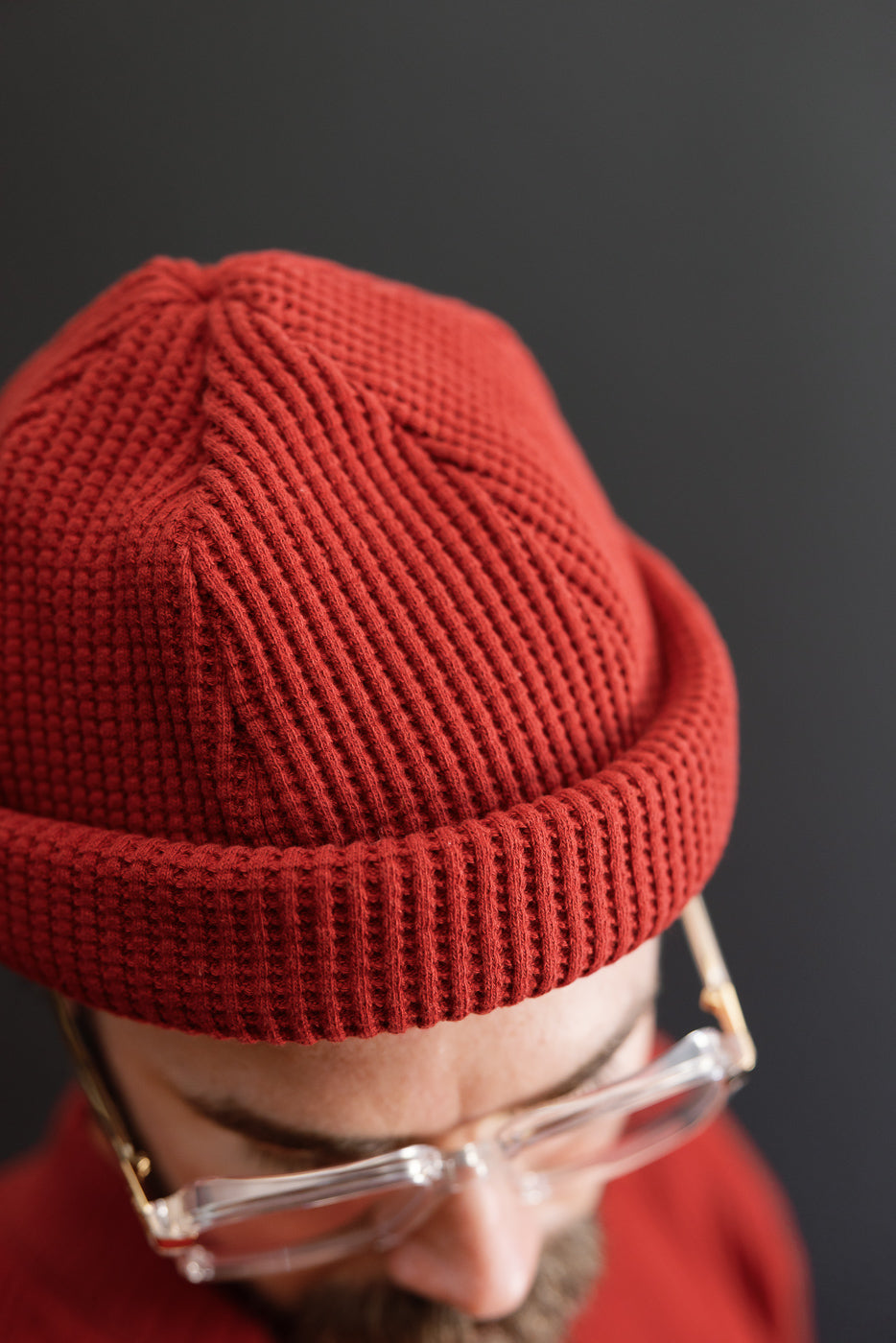 Close-up front view of red waffle knit beanie texture on a male model.