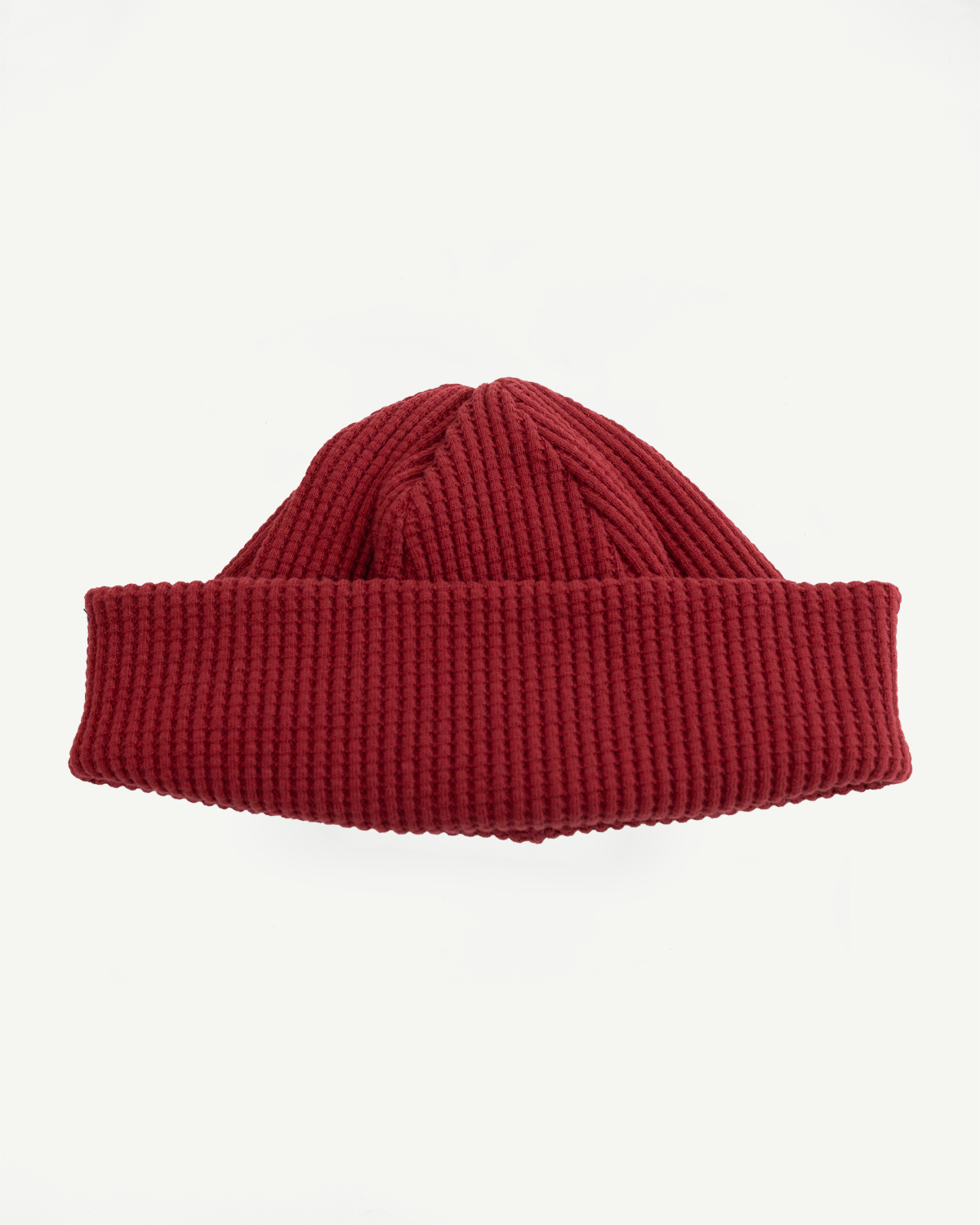 Front view close-up of a red ribbed knit beanie showing thick textured fabric.
