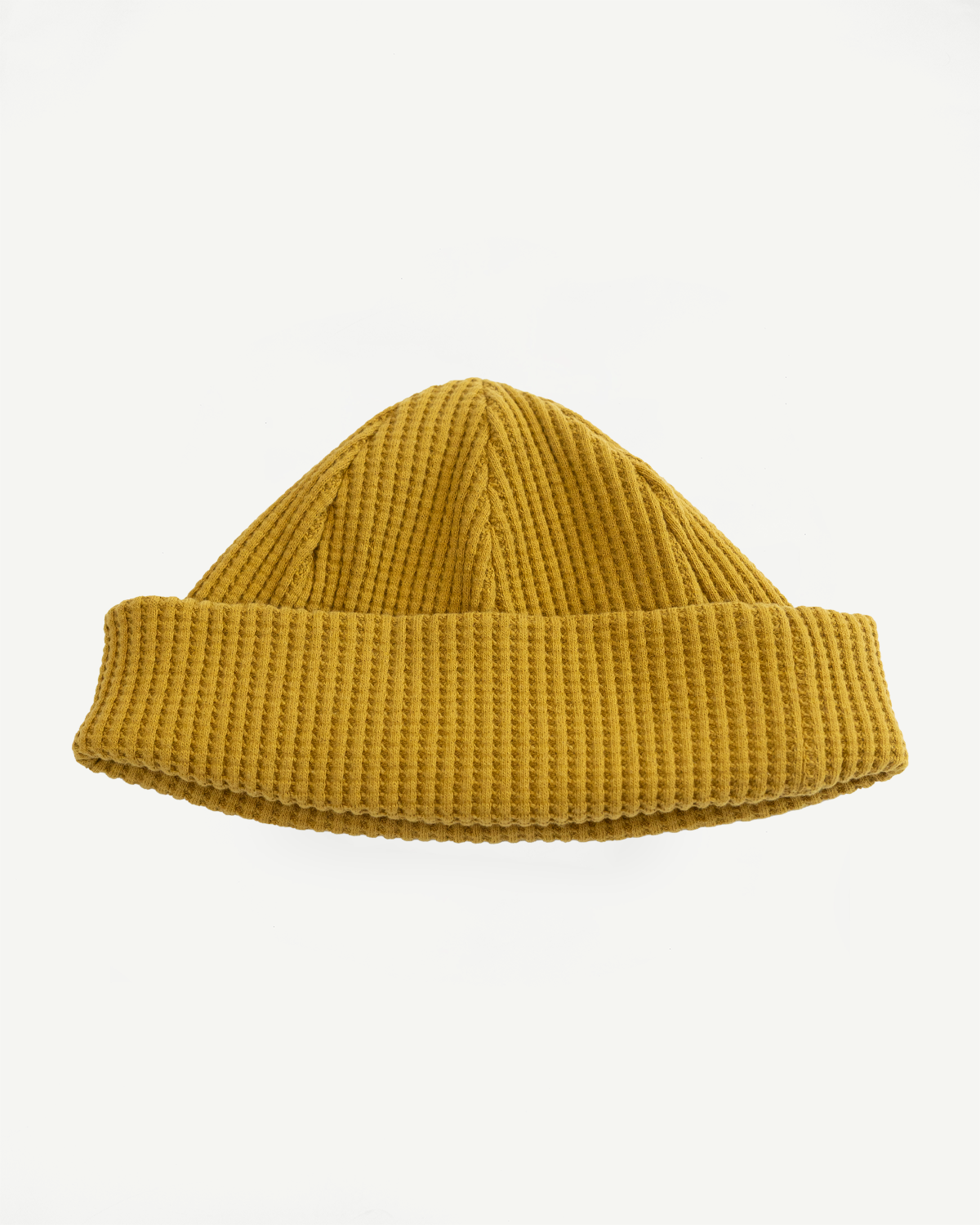 Front view flat lay of a mustard yellow waffle knit beanie hat.