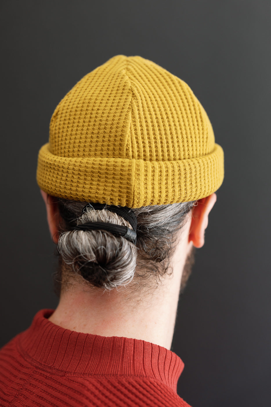 Back close-up of a male model wearing a yellow waffle-knit beanie.
