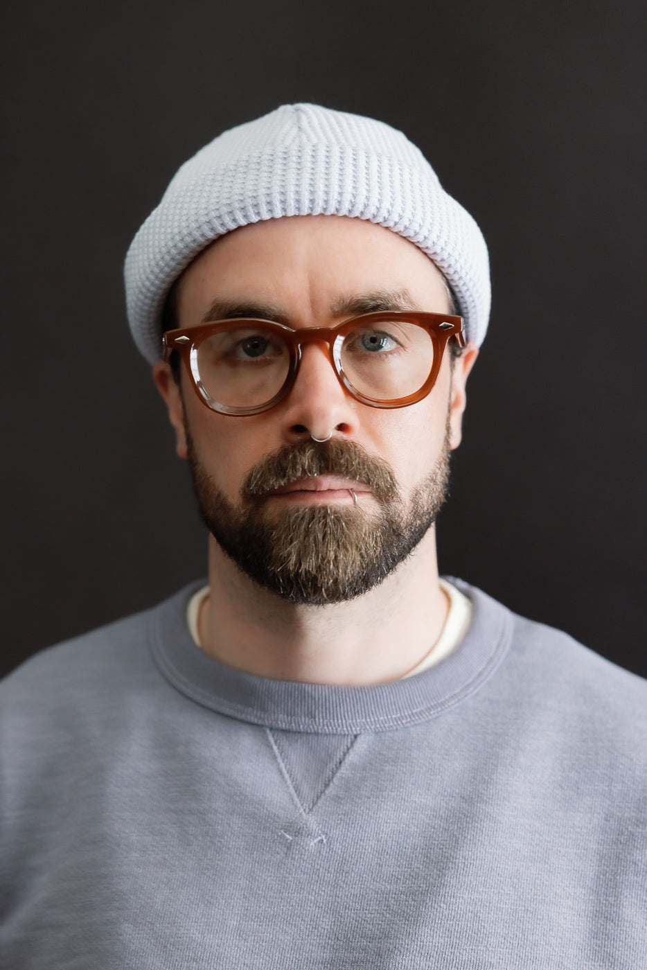 Close-up portrait of a man wearing the JM6607 - Waffle Knit Cap - 425 Ice Blue, showcasing the beanie's intricate 100% cotton waffle knit texture and versatile longer design for varied styling options.