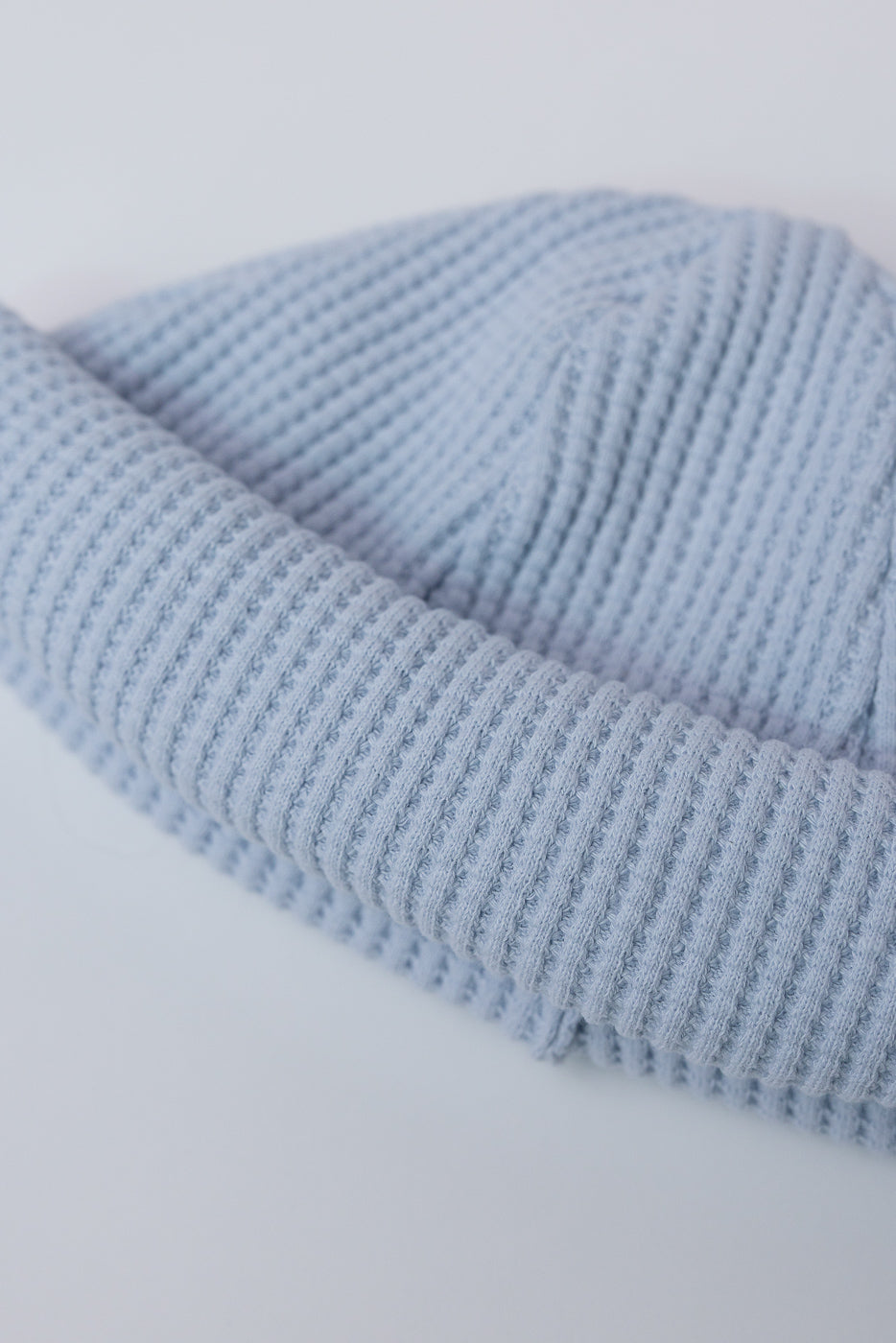 JM6607 - Waffle Knit Cap - 425 Ice Blue: A close-up of a light blue, rib-knit beanie in folded cuff style, showcasing its intricate waffle pattern, highlighting premium Japanese craftsmanship and versatile design.
