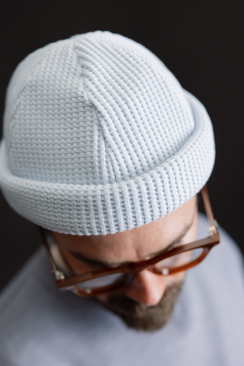 Close-up of JM6607 - Waffle Knit Cap in Ice Blue, showcasing its waffle-knit texture and cuffed design on a bearded person with tortoiseshell glasses, highlighting the cap's premium craftsmanship.