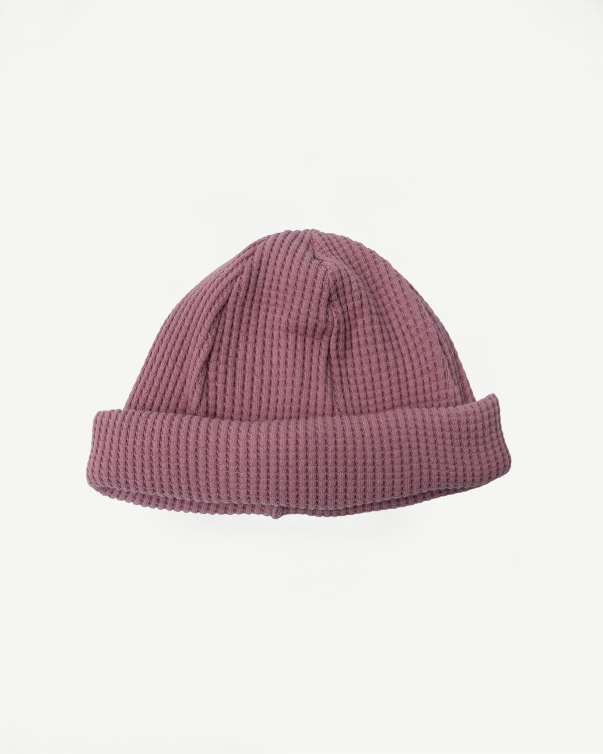 JM6607 - Waffle Knit Cap features a waffle-textured, ribbed knit in dusty pink, with a folded cuff, showcasing Jackman's premium 100% cotton craftsmanship for versatile and comfortable wear.