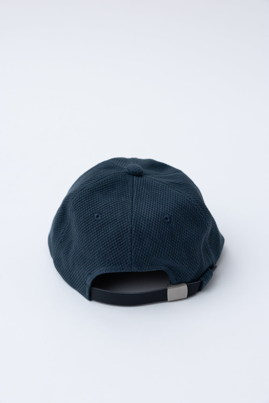 JM6623 - Sashiko BB Cap S - 280 Iron Navy features a textured, six-panel construction with sashiko fabric, an adjustable strap, and embroidered ventilation eyelets, showcasing a blend of heritage and craftsmanship.