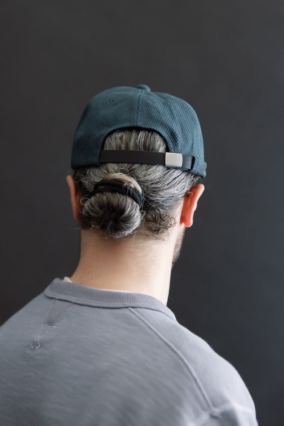 JM6623 - Sashiko BB Cap S - 280 Iron Navy worn backwards, showcasing its adjustable metal-buckled strap against a graying bun, highlighting the cap's artisanal sashiko fabric texture.