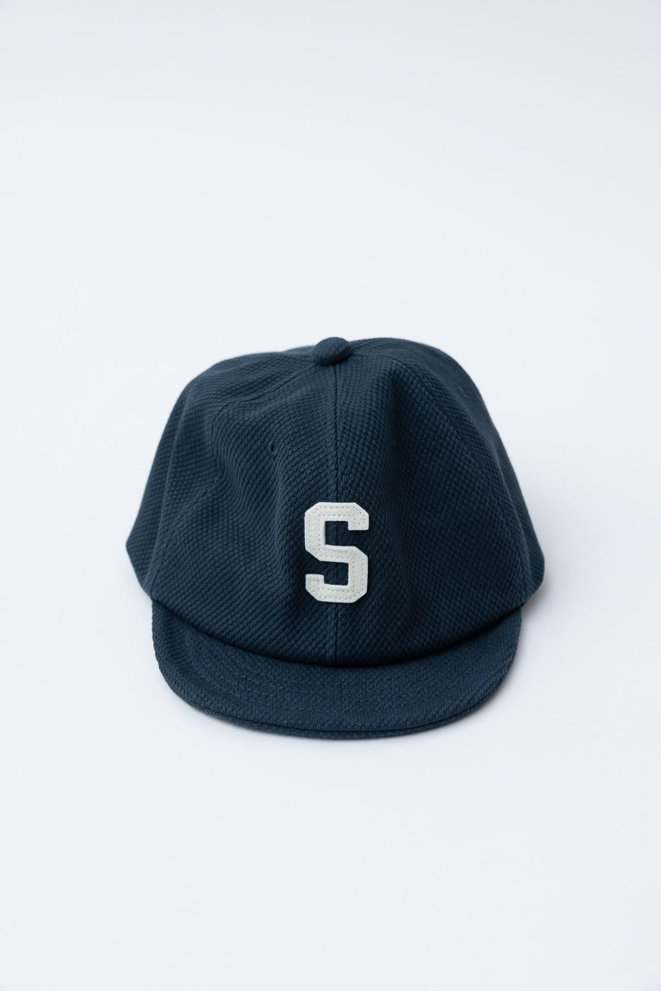JM6623 - Sashiko BB Cap S - 280 Iron Navy: A dark-navy, textured baseball cap featuring a white S embroidered on the front, crafted from sashiko fabric, echoing historical Japanese baseball materials.