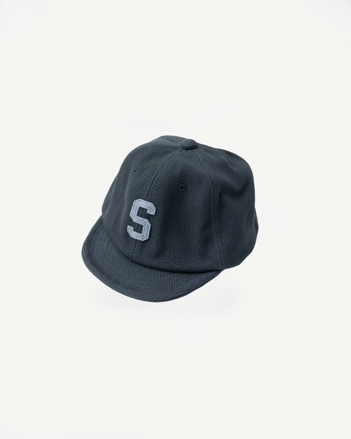 JM6623 - Sashiko BB Cap S in Falcon Gray, features a textured navy fabric with an embroidered S, highlighting its sashiko weave, embodying a rich baseball history and Japanese craftsmanship.