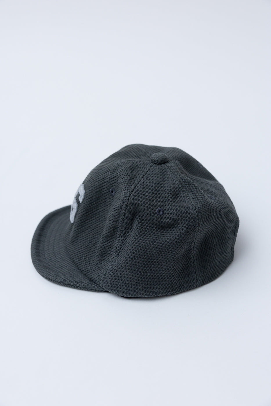 JM6623 - Sashiko BB Cap S - 333 Falcon Gray: Dark-gray baseball cap on white surface, showcasing textured sashiko fabric and subtle embroidery, reflecting Jackman's heritage-inspired design and premium craftsmanship.