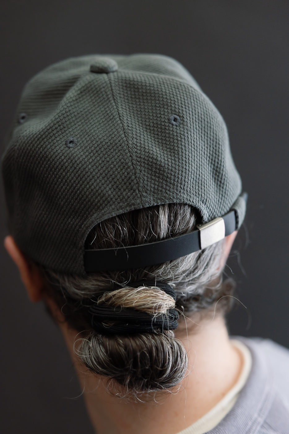 JM6623 - Sashiko BB Cap S - 333 Falcon Gray, showcasing a textured sashiko fabric and adjustable strap, worn with hair gathered into a low bun, emphasizing its unique craftsmanship and heritage.