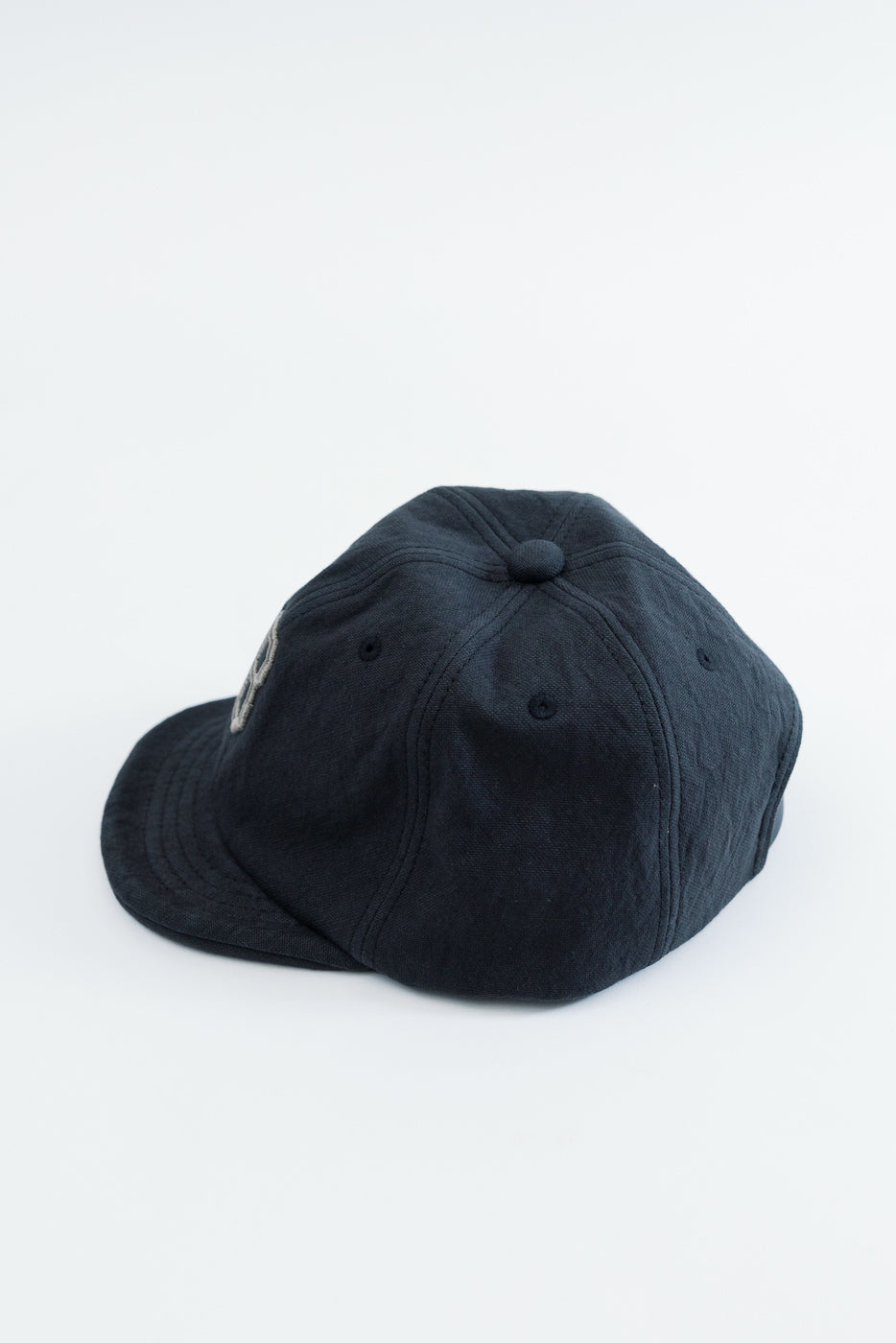 Back view close-up of a navy blue cotton baseball cap showing fabric texture and top button.
