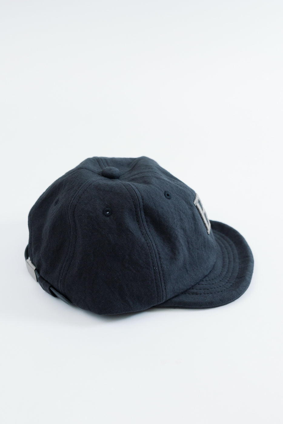 Side view close-up of a navy blue cotton baseball cap on a white background.