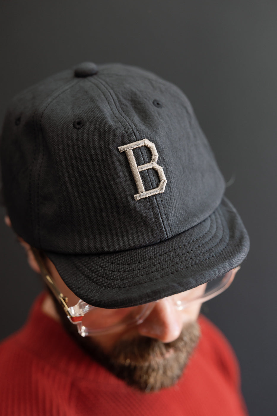 Close-up front view of a black cotton baseball cap featuring a white embroidered letter B.